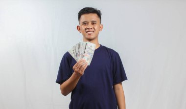 Donanma tişörtü giyen Asyalı bir adam bir sürü para tutarken mutlu görünüyor.