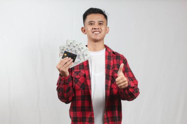 Asyalı bir adamın portresi, elinde bir yığın banknot tutuyordu. Beyaz arka planda. Başarılı genç işadamı çok para kazanıyor.