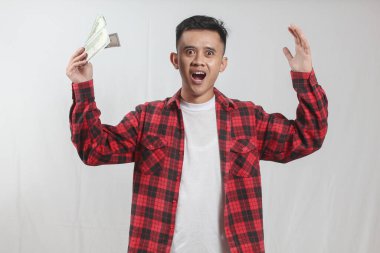 Asyalı kızgın bir adamın elinde dolar parası var. Beyaz arka planda izole edilmiş.