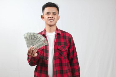 Kareli gömlek giyen Asyalı bir adam bir sürü yüz dolarlık banknot tutuyor.