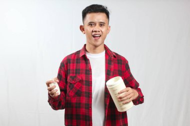 İşaretli gömlek giyen Asyalı adam plastik bir kavanoz açıyor.