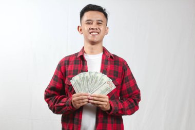 Kareli gömlek giyen Asyalı bir adam bir sürü yüz dolarlık banknot tutuyor.