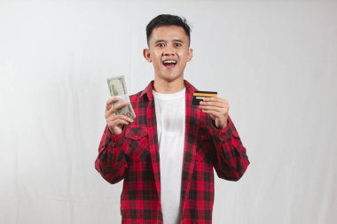 Kareli tişört giyen Asyalı bir adam yüksek kaliteli siyah kredi kartı ve dolar banknotu tutuyor.