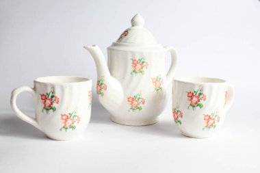 Beyaz arka planda izole edilmiş çiçek desenli beyaz seramik çaydanlık ve fincan