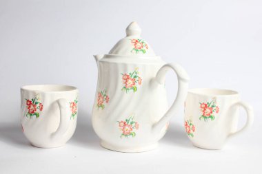 Beyaz arka planda izole edilmiş çiçek desenli beyaz seramik çaydanlık ve fincan