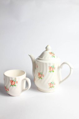 Beyaz arka planda izole edilmiş çiçek desenli beyaz seramik çaydanlık ve fincan