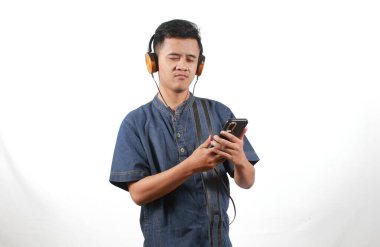 Kot gömlek giyen Asyalı adam kulaklıkla müzik dinlemekten hoşlanıyor.