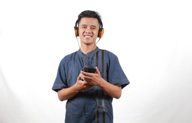 Kot gömlek giyen Asyalı adam kulaklıkla müzik dinlemekten hoşlanıyor.