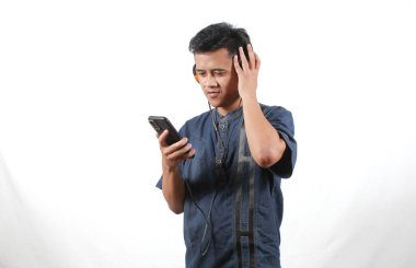 Kot gömlek giyen Asyalı adam kulaklıkla müzik dinlemekten hoşlanıyor.