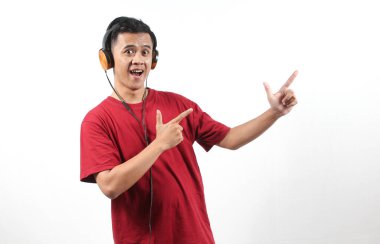 Neşeli Asyalı adam kulaklıklardan en sevdiği şarkıyı dinlerken parmağını fotokopi alanına doğrultuyor.