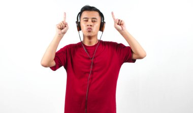 Asyalı bir adam kulaklıkla parmaklarını kaldırırken gözleri kapalı müzikten hoşlanıyor.