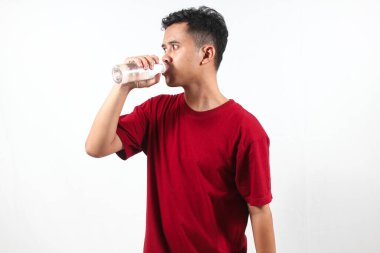 Asyalı adam şeffaf plastik şişeden maden suyu içiyor.