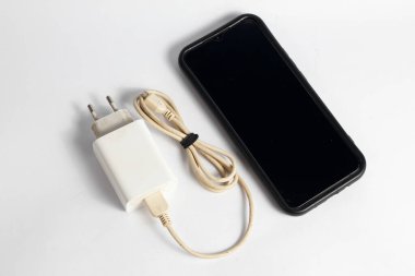 Şarj aleti ve ölü akıllı telefon beyaz arkaplanda izole edilmiş.