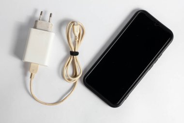 Şarj aleti ve ölü akıllı telefon beyaz arkaplanda izole edilmiş.