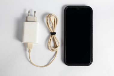 Şarj aleti ve ölü akıllı telefon beyaz arkaplanda izole edilmiş.