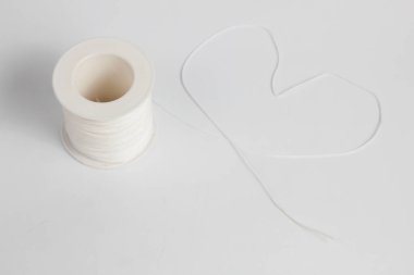 Beyaz naylon iplik plastik bir kılıfa düzgünce sarılmış, sicim beyaz bir arka planda izole edilmiş bir kalp şekli oluşturuyor.