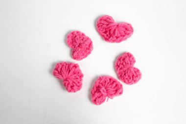 Pembe yün kumaştan yapılmış, beyaz arka planda izole edilmiş kalp şeklinde el yapımı aksesuar.