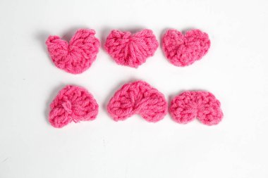Pembe yün kumaştan yapılmış, beyaz arka planda izole edilmiş kalp şeklinde el yapımı aksesuar.