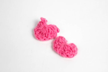 Pembe yün kumaştan yapılmış, beyaz arka planda izole edilmiş kalp şeklinde el yapımı aksesuar.