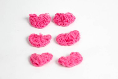 Pembe yün kumaştan yapılmış, beyaz arka planda izole edilmiş kalp şeklinde el yapımı aksesuar.