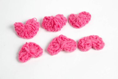 Pembe yün kumaştan yapılmış, beyaz arka planda izole edilmiş kalp şeklinde el yapımı aksesuar.