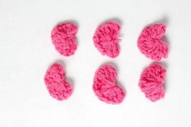 Pembe yün kumaştan yapılmış, beyaz arka planda izole edilmiş kalp şeklinde el yapımı aksesuar.