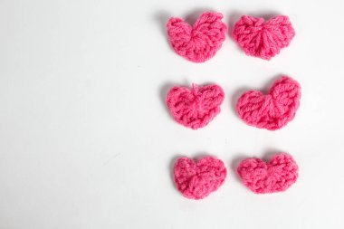 Pembe yün kumaştan yapılmış, beyaz arka planda izole edilmiş kalp şeklinde el yapımı aksesuar.