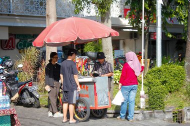 Endonezya, Solo - 1 Haziran 2025: Bir grup alıcı yemek kuyruğunda, yol kenarındaki bir el arabasından yumurta kabuğu yuvarladılar..