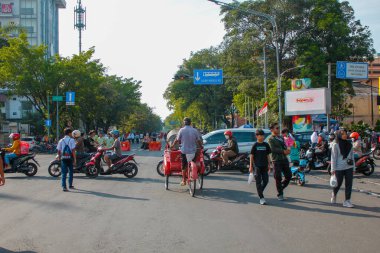 Endonezya, Solo - 1 Haziran 2025: Çocuk taksi şoförleri yaya ve yayalar yoğun yolu geçmekte zorlanıyorlar. Trafiğin kontrolü, kırmızı ışıkta geçen araçlar..