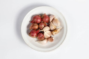 Beyaz arkaplanda izole edilmiş bir tabakta kırmızı ve beyaz soğan