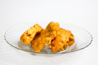 Sebze ve kızarmış tempeh ile doldurulmuş kızarmış tofu şeffaf cam bir tabakta servis edilir, beyaz arka planda izole edilir.