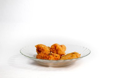 Sebze ve kızarmış tempeh ile doldurulmuş kızarmış tofu şeffaf cam bir tabakta servis edilir, beyaz arka planda izole edilir.