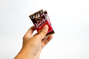 Indonesia, Sukoharjo - June 19, 2025 : holding a sachet of ground coffee product  steamer (Kapal Api )brand from Indonesia, Isolated on white background