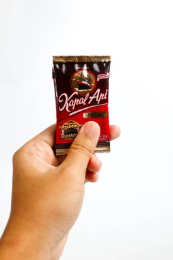 Indonesia, Sukoharjo - June 19, 2025 : holding a sachet of ground coffee product  steamer (Kapal Api )brand from Indonesia, Isolated on white background