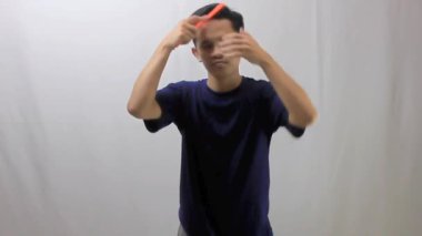 Beyaz arka planda plastik tarakla saç tarayan Asyalı bir adam.