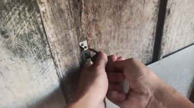Eller yıpranmış ahşap bir kapının kilidini açmak için anahtar kullanır. Kırsal alanda klasik güvenlik önlemlerinin önemini vurgularlar..