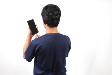 Donanma tişörtü giyen Asyalı adam elinde akıllı telefon ile beyaz arka planda izole edilmiş şarj edilebilir güç kablosu yerleştiriyor. Akıllı telefon şarj kavramı.