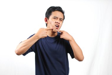 Asyalı bir adam çenesine sivilce bastırıyor. Yüzünde acı ifadesi var. Beyaz arka planda izole edilmiş.