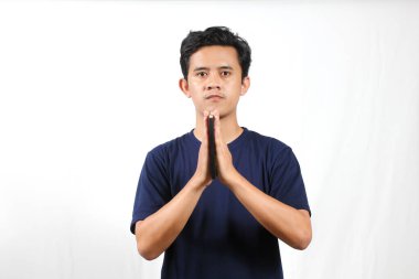 Genç adam naçizane bir şekilde el ele tutuşup huzur ve rehberlik arayarak huzur içinde dua veya tefekkür ederken kitabı tutuyor.