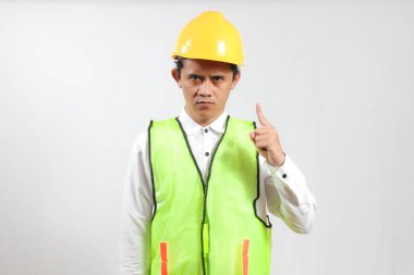 Maden işçisi, iş yerinde kask ve yelek giyerek güvenliği sağlamak için kaskına işaret ederken rahatsız edici bir ifade sergiledi..