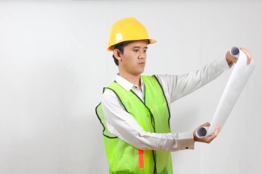 Asyalı inşaat işçisi elinde projeyle beyaz arka planda ciddi şekilde izole edilmiş görünüyor. Konsept mühendisi ve iş adamı. Başarı.