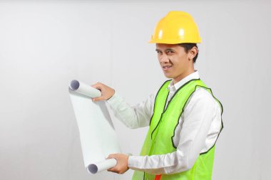 Asyalı inşaat işçisi elinde projeyle beyaz arka planda ciddi şekilde izole edilmiş görünüyor. Konsept mühendisi ve iş adamı. Başarı.