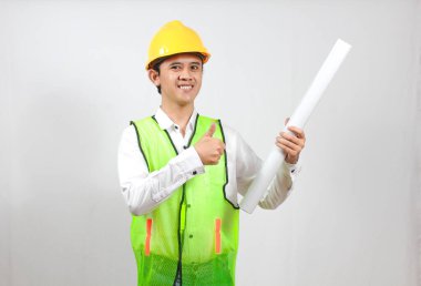 İnşaat işçisi elinde plan tutarken beyaz arka planda izole bir şekilde gülümserken baş parmak işareti veriyor.