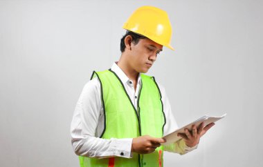 İnşaat yöneticisi, bina inşaat raporlarını ciddi ve dikkatlice kontrol ediyor. Beyaz bir arka planda izole edilmiş..