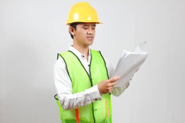 İnşaat yöneticisi, bina inşaat raporlarını ciddi ve dikkatlice kontrol ediyor. Beyaz bir arka planda izole edilmiş..