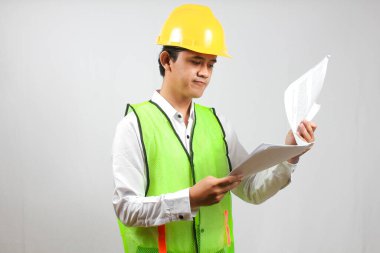 İnşaat yöneticisi, bina inşaat raporlarını ciddi ve dikkatlice kontrol ediyor. Beyaz bir arka planda izole edilmiş..