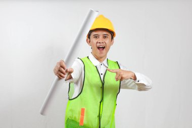 İnşaat işçisi elinde tuttuğu planı işaret ederek mutlu ve coşkulu bir şekilde beyaz arka planda izole etti.