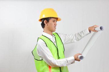 Bir inşaat işçisi elinde bir proje tutuyor, beyaz arka planda izole edilmiş bir binanın ayrıntılı çizimine dikkatle bakıyor. Kavramsal mühendislik ve iş çalışmaları