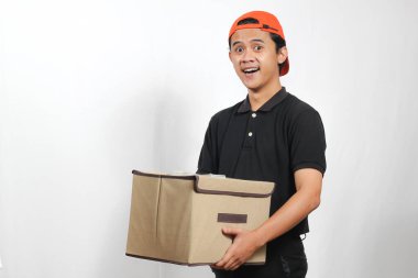 Siyah polo tişört ve turuncu şapka giyen gülümseyen teslimat çalışanı bir paket kutusu tutuyor ve müşterinin gideceği adrese teslim ediyor. Servis kavramı