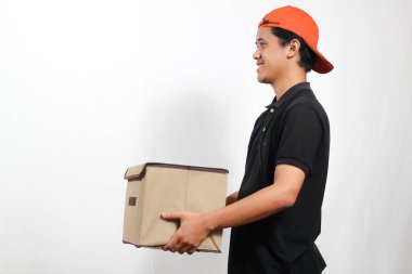 Siyah polo tişört ve turuncu şapka giyen gülümseyen teslimat çalışanı bir paket kutusu tutuyor ve müşterinin gideceği adrese teslim ediyor. Servis kavramı